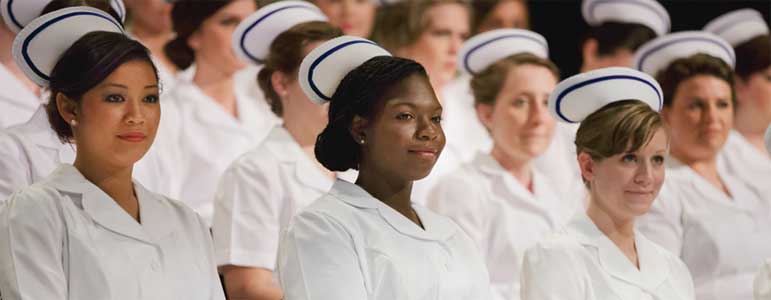 A black nurse amidst other white nurses apparently all receiving accolades.